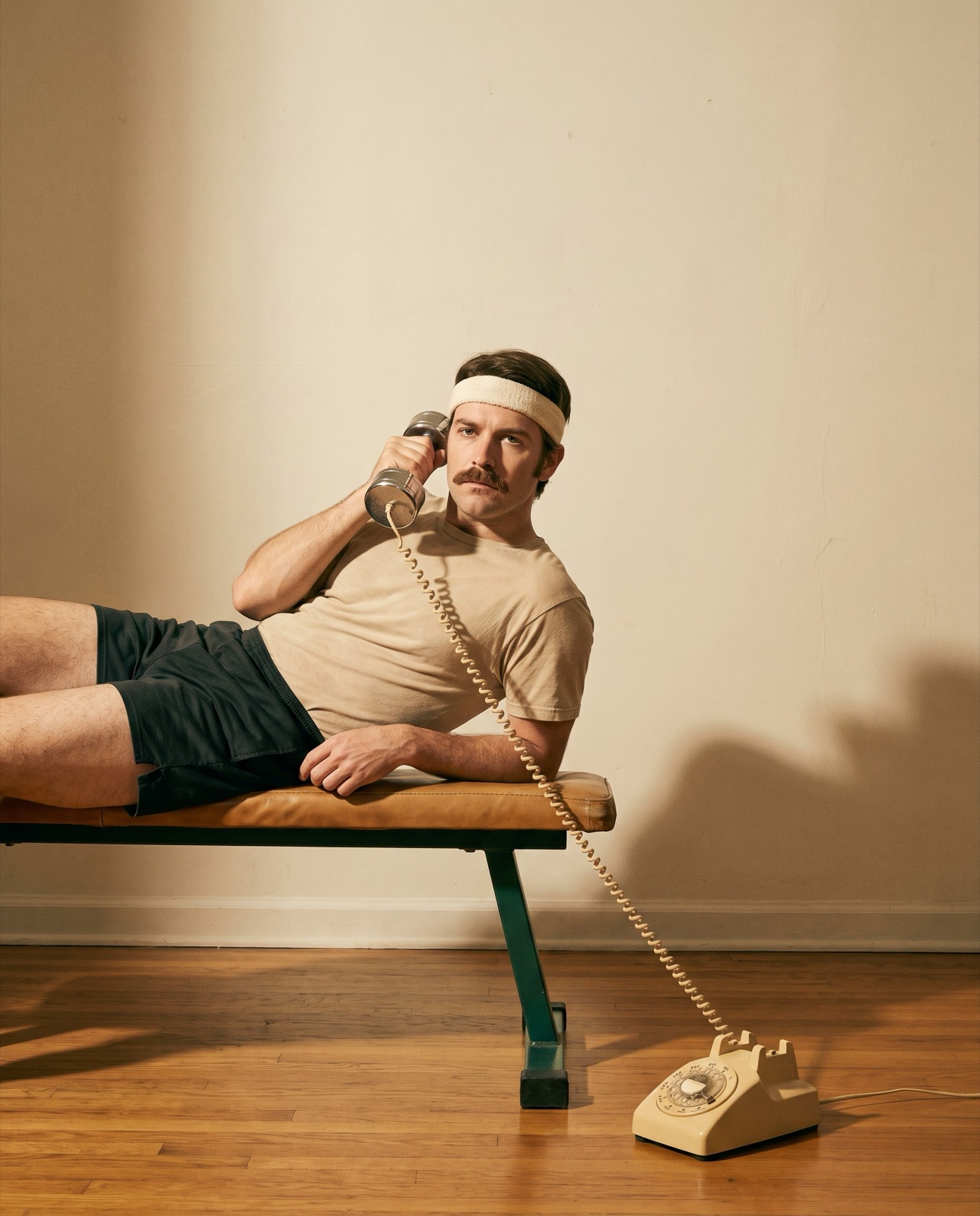 Person im Retro-Sportlook hält eine Hantel wie einen Telefonhörer ans Ohr